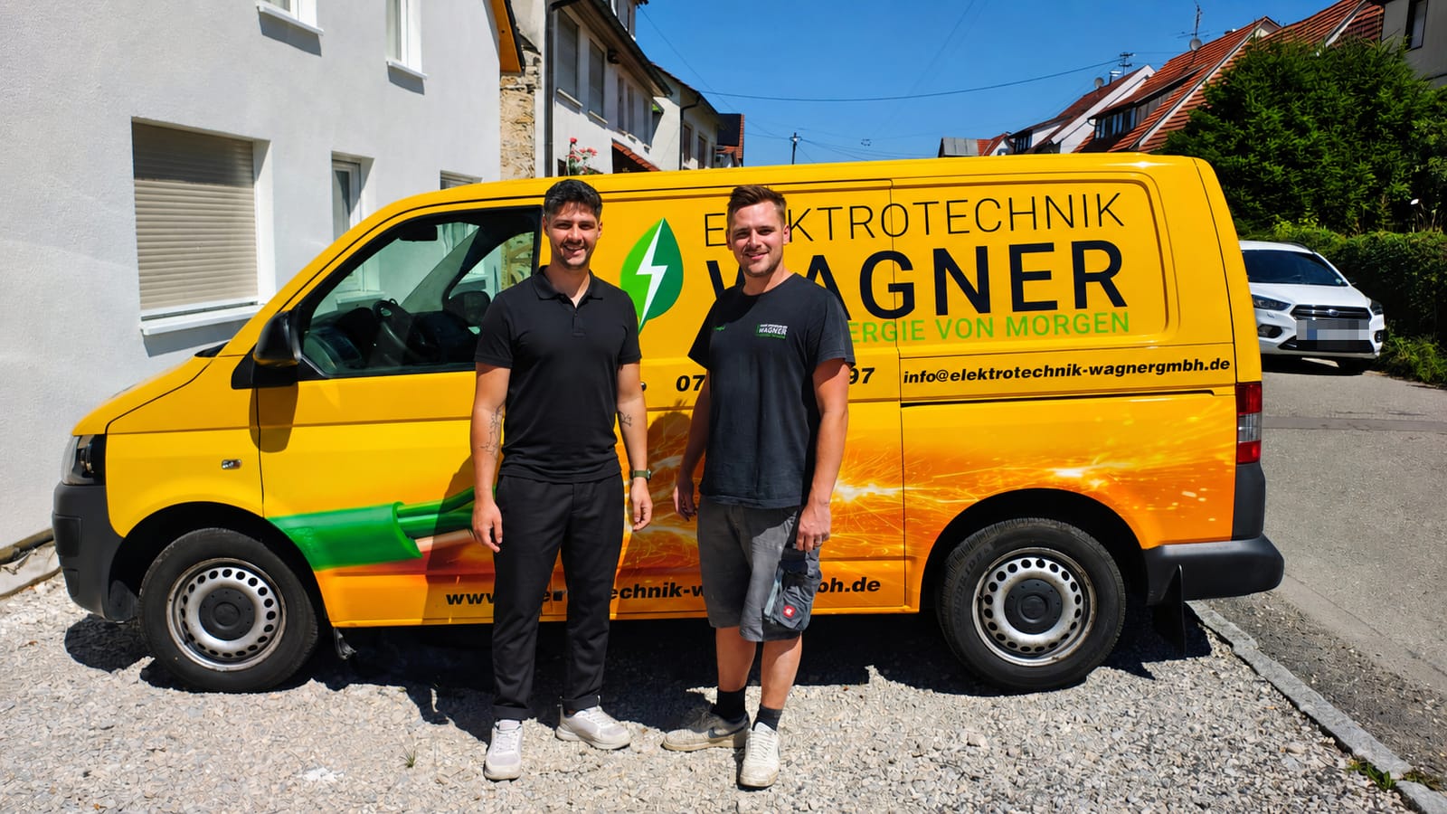 Timo Reum von Zurück zum Kerngeschäft (links) und Tobias Wagner, Inhaber der Elektrotechnik Wagner GmbH (rechts), vor dem beschrifteten Firmentransporter des Elektrobetriebs.